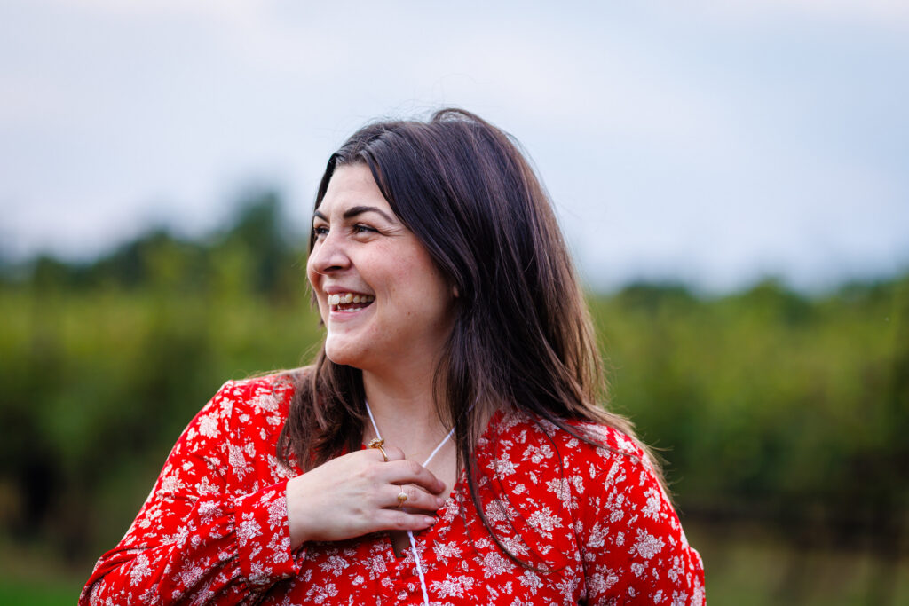 A woman in a red shirt is smiling and looking left.
